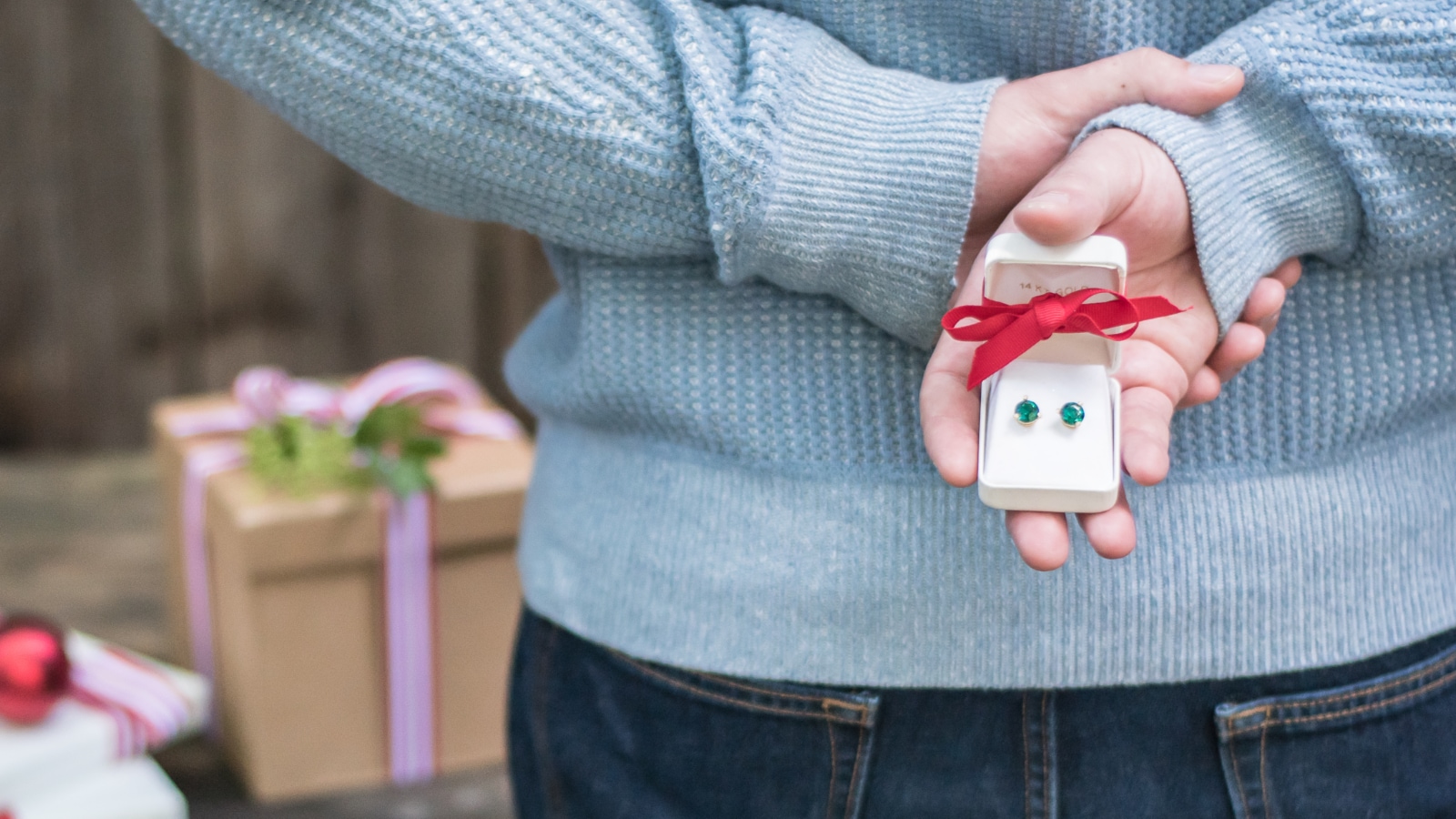 man holding earrings gift behind his back